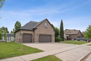 View of front of home with brick siding, a front lawn, concrete driveway, and cooling unit