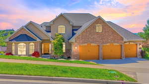 View of front of property with stucco siding, concrete driveway, brick siding, and a garage