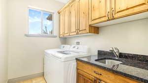 Washroom with washing machine and dryer, cabinet space, baseboards, and light tile patterned flooring