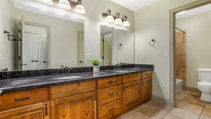 Bathroom featuring toilet, double vanity, and bathtub / shower combination