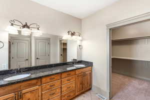 Full bath featuring double vanity, a walk in closet, and baseboards