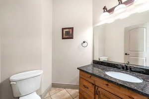Bathroom with toilet, vanity, tile patterned flooring, and baseboards