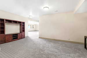Unfurnished living room featuring carpet and baseboards