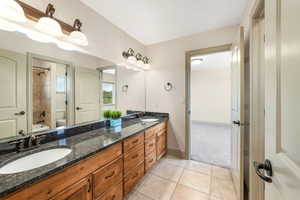 Full bathroom with toilet, double vanity, shower / washtub combination, tile patterned floors, and baseboards