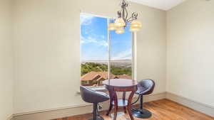 Dining room with wood finished floors, a chandelier, and baseboards