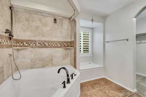 Bathroom featuring a bath, a shower, a walk in closet, and baseboards