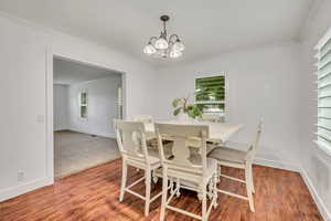 Dining room featuring a chandelier, ornamental molding, baseboards, and wood finished floors