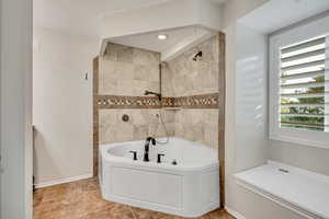 Bathroom with a bathtub, a shower, and baseboards