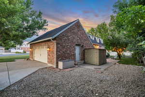 View of side of home featuring brick siding, an attached garage, concrete driveway, and roof with shingles