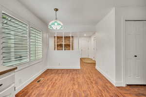 Unfurnished dining area with wood finished floors, baseboards, and a chandelier