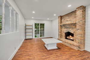 Unfurnished living room with recessed lighting, wood finished floors, a brick fireplace, and baseboards