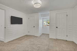 Unfurnished bedroom with a textured ceiling, carpet flooring, and a closet