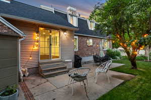 Patio terrace at dusk with entry steps, a patio, and a lawn
