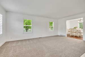 Carpeted spare room featuring crown molding, plenty of natural light, and baseboards