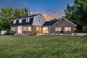 View of front of house with a chimney, brick siding, a gambrel roof, and roof with shingles