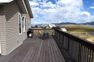 Wooden deck with a mountain view, outdoor dining space, and a grill