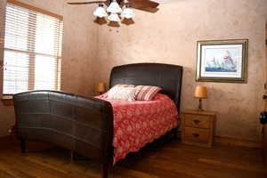 Bedroom with hardwood / wood-style floors, baseboards, and a ceiling fan