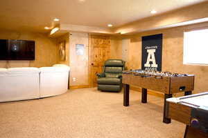Game room with carpet floors, a textured ceiling, recessed lighting, electric panel, and a textured wall