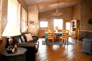 Living room featuring a chandelier, vaulted ceiling, hardwood / wood-style flooring, and a wood stove