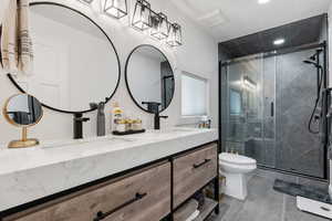 Primary ensuite bathroom with double vanity, toilet, a tiled shower, and recessed lighting