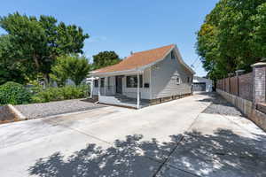 Front view of property featuring a porch, xeriscaping, long driveway and a detached garage