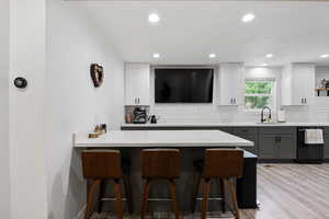 Kitchen featuring black dishwasher, a kitchen island, tasteful backsplash, white/gray cabinetry, and recessed lighting