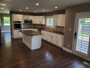 Kitchen featuring stainless steel appliances, dark countertops, recessed lighting, baseboards, and plenty of natural light