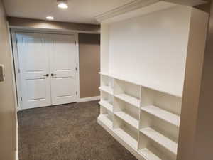 Hallway with dark carpet, recessed lighting, and baseboards