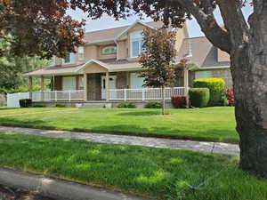 View of front of house featuring brick siding, covered porch, a shingled roof, a front lawn, and stucco siding