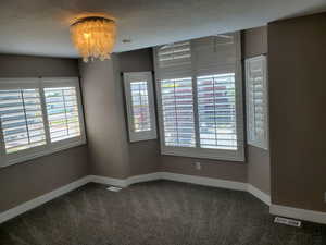 Carpeted spare room with baseboards and a chandelier