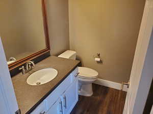 Bathroom with wood finished floors, vanity, toilet, and baseboards