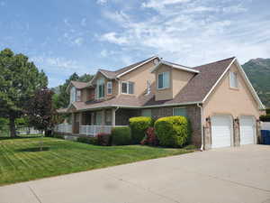 Traditional home featuring stucco siding, a porch, driveway, and roof with shingles