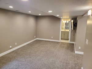 Finished below grade area with light carpet, baseboards, recessed lighting, and a sink