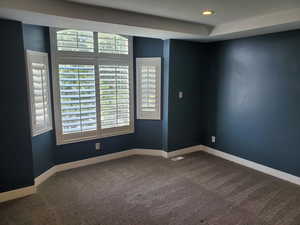 Empty room featuring dark colored carpet, baseboards, and recessed lighting