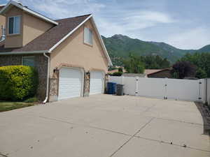 View of home's exterior with a gate, stucco siding, a mountain view, and roof with shingles