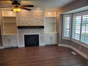 Unfurnished living room with baseboards, healthy amount of natural light, dark wood finished floors, and a ceiling fan