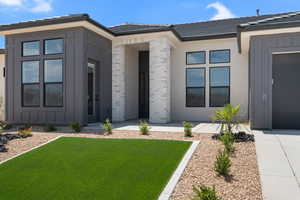 Entrance to property featuring a lawn, a garage, board and batten siding, and brick siding
