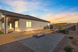 Back of house at dusk with a patio, a fire pit, a fenced backyard, and stucco siding
