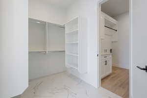 Spacious closet featuring light marble finish flooring