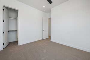 Unfurnished bedroom with carpet flooring, a closet, ceiling fan, recessed lighting, and a walk in closet
