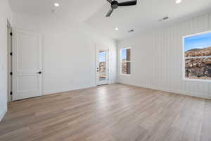 Empty room featuring healthy amount of natural light, a ceiling fan, lofted ceiling, light wood finished floors, and recessed lighting