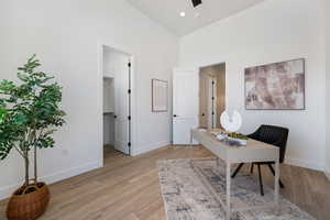 Office space featuring high vaulted ceiling and light wood-style flooring