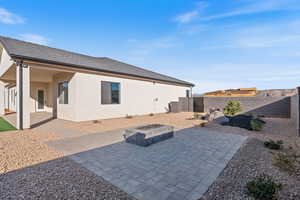 Rear view of property featuring a patio area, an outdoor fire pit, stucco siding, and a fenced backyard