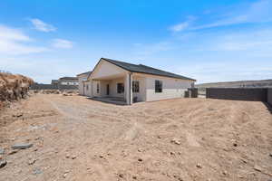 Back of house with stucco siding, cooling unit, and a patio area