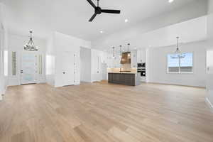 Unfurnished living room featuring a chandelier, baseboards, a ceiling fan, recessed lighting, and light wood-style floors