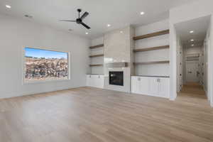 Unfurnished living room with ceiling fan, light wood finished floors, a tiled fireplace, recessed lighting, and baseboards
