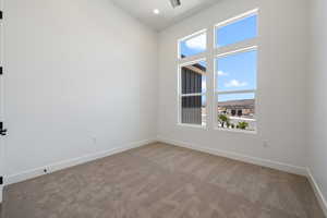 Carpeted empty room with a high ceiling and recessed lighting