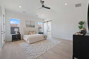 Bedroom featuring light wood-type flooring, a barn door, recessed lighting, a ceiling fan, and lofted ceiling