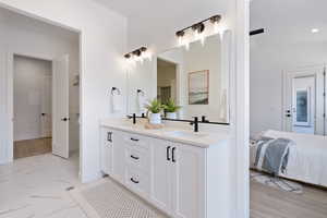 Bathroom featuring double vanity, ensuite bath, recessed lighting, and marble finish flooring