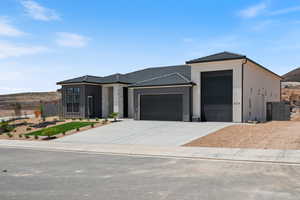 View of front of property featuring a garage, driveway, a tile roof, board and batten siding, and stucco siding